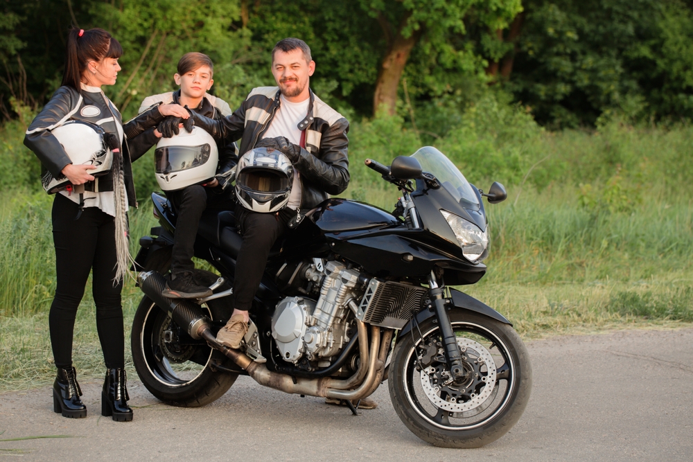 Famille de motards casques en main près de leur moto